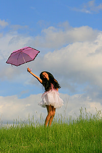 woman wearing pink and white dress holding pink umbrella standing on green grass during daytime thumbnail