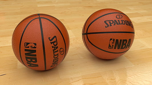 two brown Spalding NBA basketballs on wooden floor thumbnail