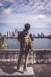 Man Carrying Backpack Looking At Ferris Wheel thumbnail
