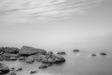 grayscale photography of rock formation near shore thumbnail