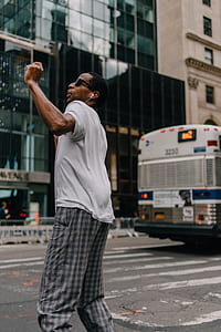 close-up photography of man standing near pedestrian lane while dancing at daytime thumbnail
