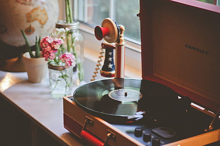 Crosley turntable near candlestick phone beside pink clustered flowers in clear glass mason jar thumbnail