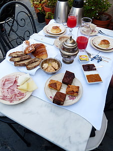 baked breads, clear drinking glasses, and food placed on white table thumbnail