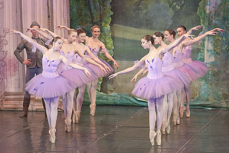 eight women in purple tutu dresses dancing ballet on stage thumbnail