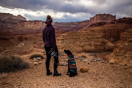 woman standing beside dog viewing rock formation thumbnail