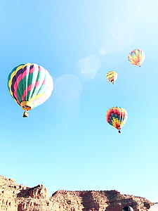 four assorted-color of hot air balloons over rocky mountains thumbnail