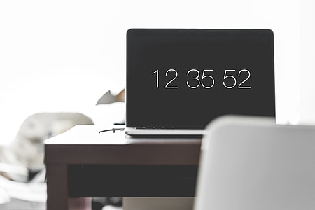Laptop with Time Screen Saver on Office Desk thumbnail