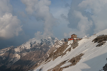 brown and red building on top of snow capped mountain thumbnail