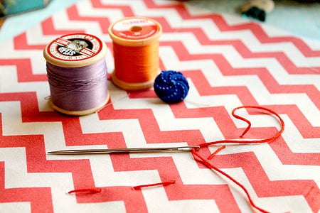 two thread spools near white knitting pin thumbnail