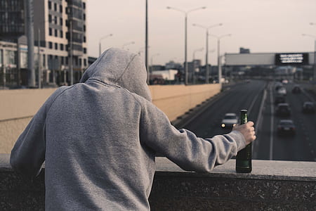 person wearing gray pullover hoodie holding bottle thumbnail