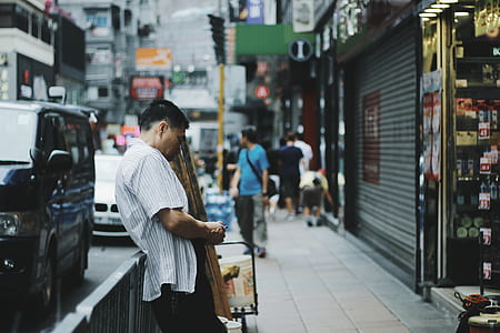 shallow focus photography of man standing in front of store front thumbnail