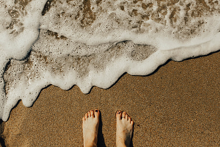 person standing on beach sand near ocean waves thumbnail