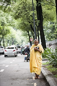 Monk Holding Bowl While Walking on Street thumbnail