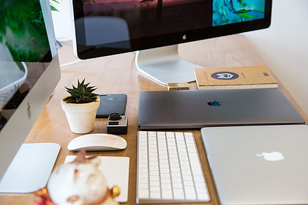 gray laptop computer on table near keyboard and monitors thumbnail