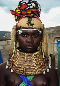 woman wearing brown and black turban and necklace standing near building at daytime thumbnail