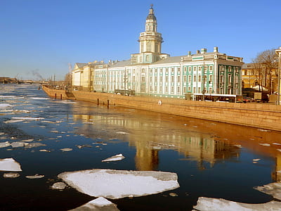 white and brown concrete building beside body of water under blue sky at daytime thumbnail