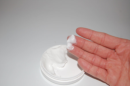 person's hand with white cream near white container thumbnail