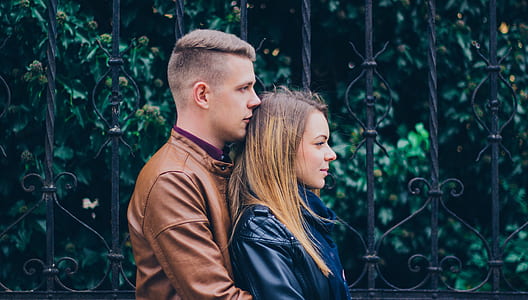 man hugging woman near gate at daytime thumbnail