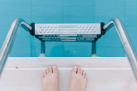 person standing on edge of pool in front pool ladder thumbnail