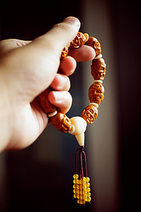 person holding brown prayer beads thumbnail