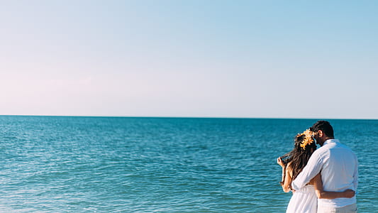 woman and man wearing white top beside body of water under white clouds thumbnail