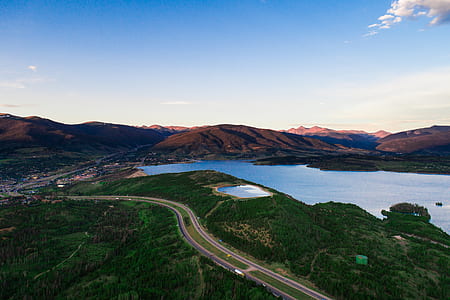 aerial view of road near body of water and mountains during daytime thumbnail