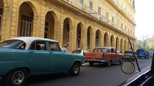 two green and red classic soft-top sedan on read near brown concrete building during daytime thumbnail