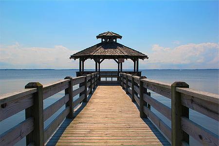 brown wooden dock with gazebo surrounded by body of water during daytime thumbnail