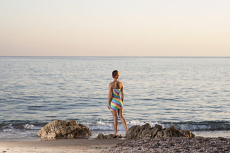 woman standing and facing body of water thumbnail