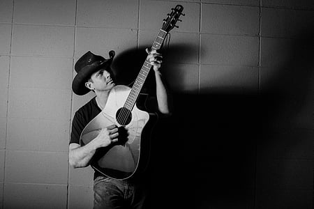grayscale photography of man carrying guitar thumbnail
