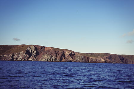 body of water near mountains under clear sky thumbnail