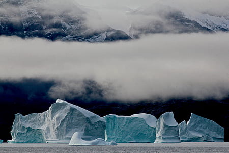 blue and white iceberg under cloudy skies thumbnail