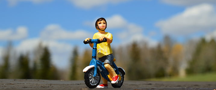 depth of field photo of boy riding blue bicycle thumbnail