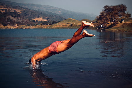 photo of man in red shorts about to dive on body of water thumbnail