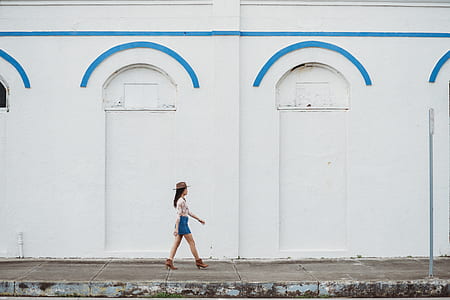 woman in white top and blue bottom walking on street during daytime thumbnail