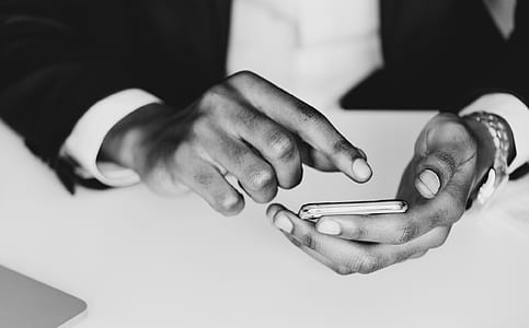 grayscale photo of man holding smartphone thumbnail