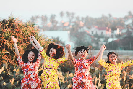 four women wearing yellow and red dresses thumbnail