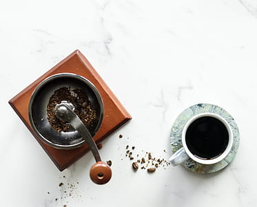 flat lay photography of manual coffee mill beside teacup thumbnail