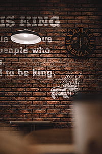 black analog clock mounted on brown concrete brick wall thumbnail