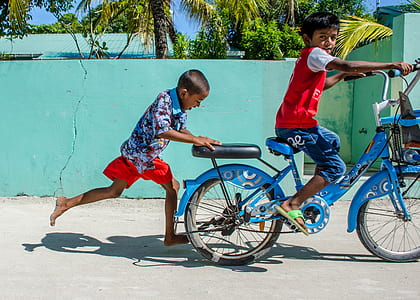 boy riding bicycle pushed by another boy thumbnail
