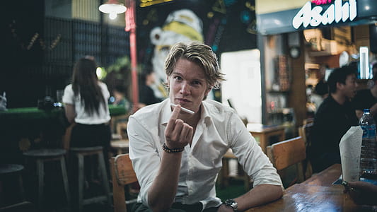 man in white dress shirt sitting on chair while holding cigarette thumbnail