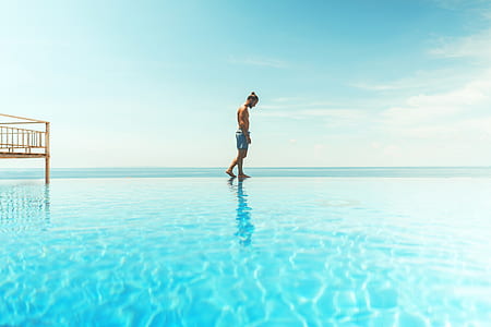 man walking on body of water under blue sky during daytime thumbnail