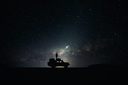 man standing looking through the sky on truck silhouette photography thumbnail