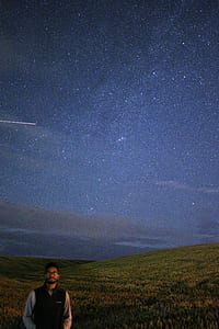 man standing on greenfield under milky way thumbnail