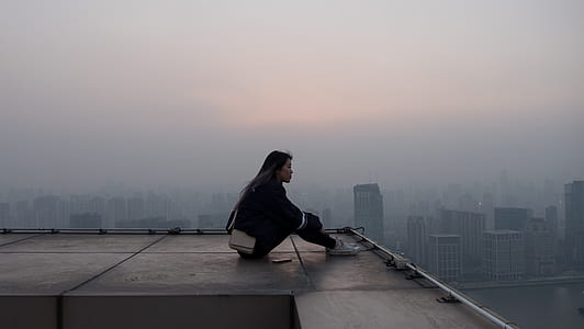 woman in black jacket and pants sitting on roof top thumbnail