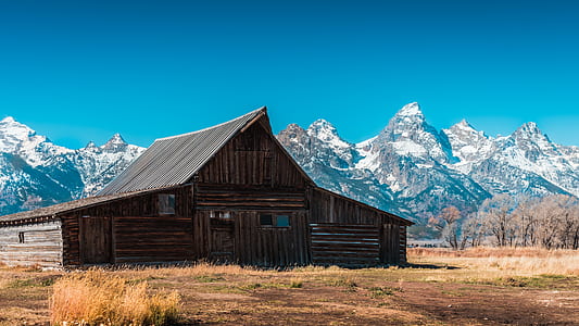 brown wooden barn house near mountain at daytime thumbnail
