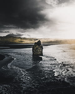 brown rock formation in the middle of beach thumbnail