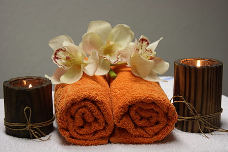 two orange towels beside brown votive candles thumbnail