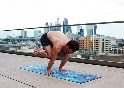 man doing yoga on rooftop during day thumbnail