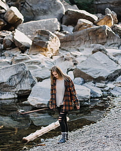 woman standing near body of water with pile of rocks thumbnail